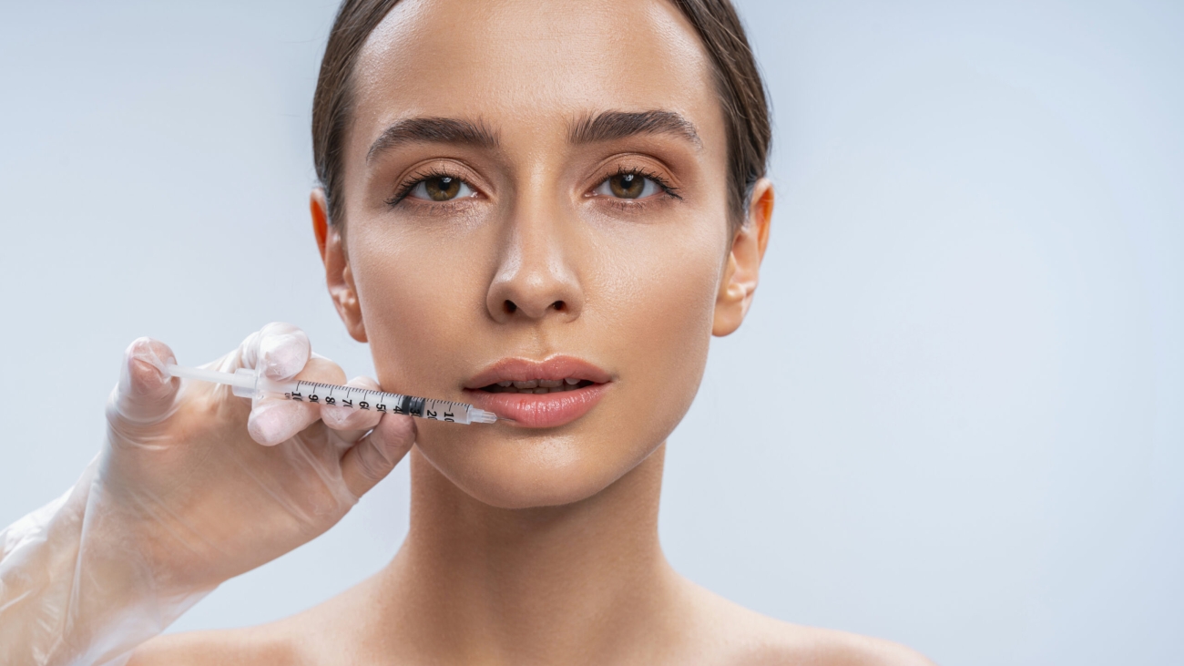Cute girl looking forward while doing injection in her lips